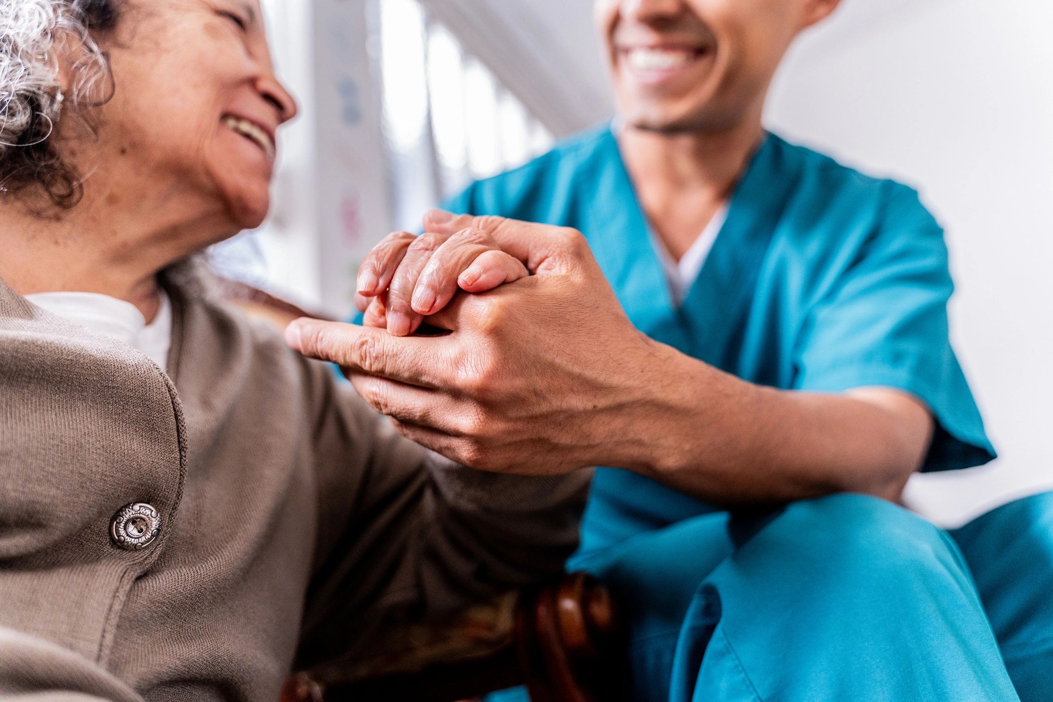 Caregiver holding an older woman's hands in reassurance