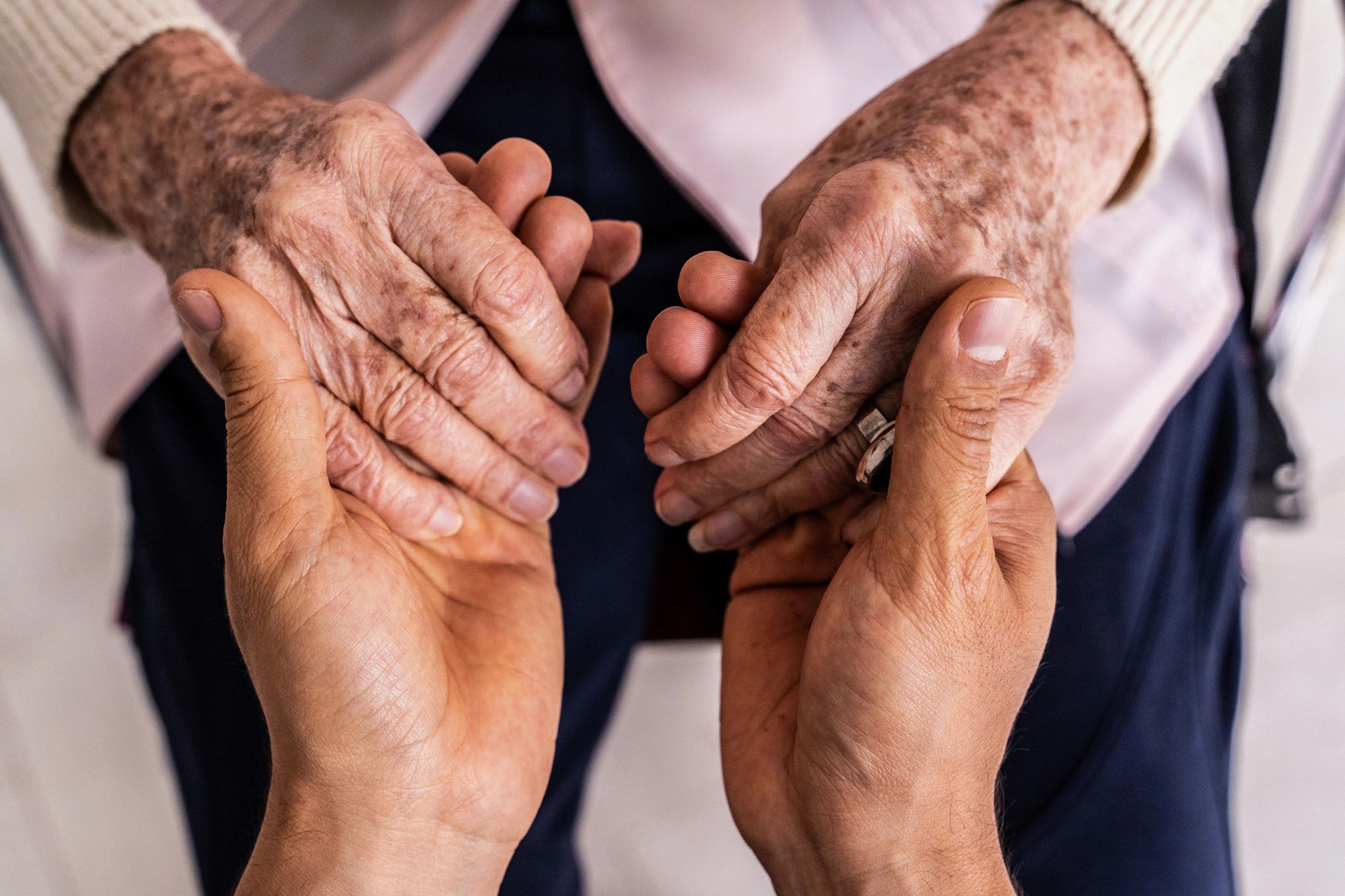 Caregiver holding an older woman’s hands in a reassuring gesture.