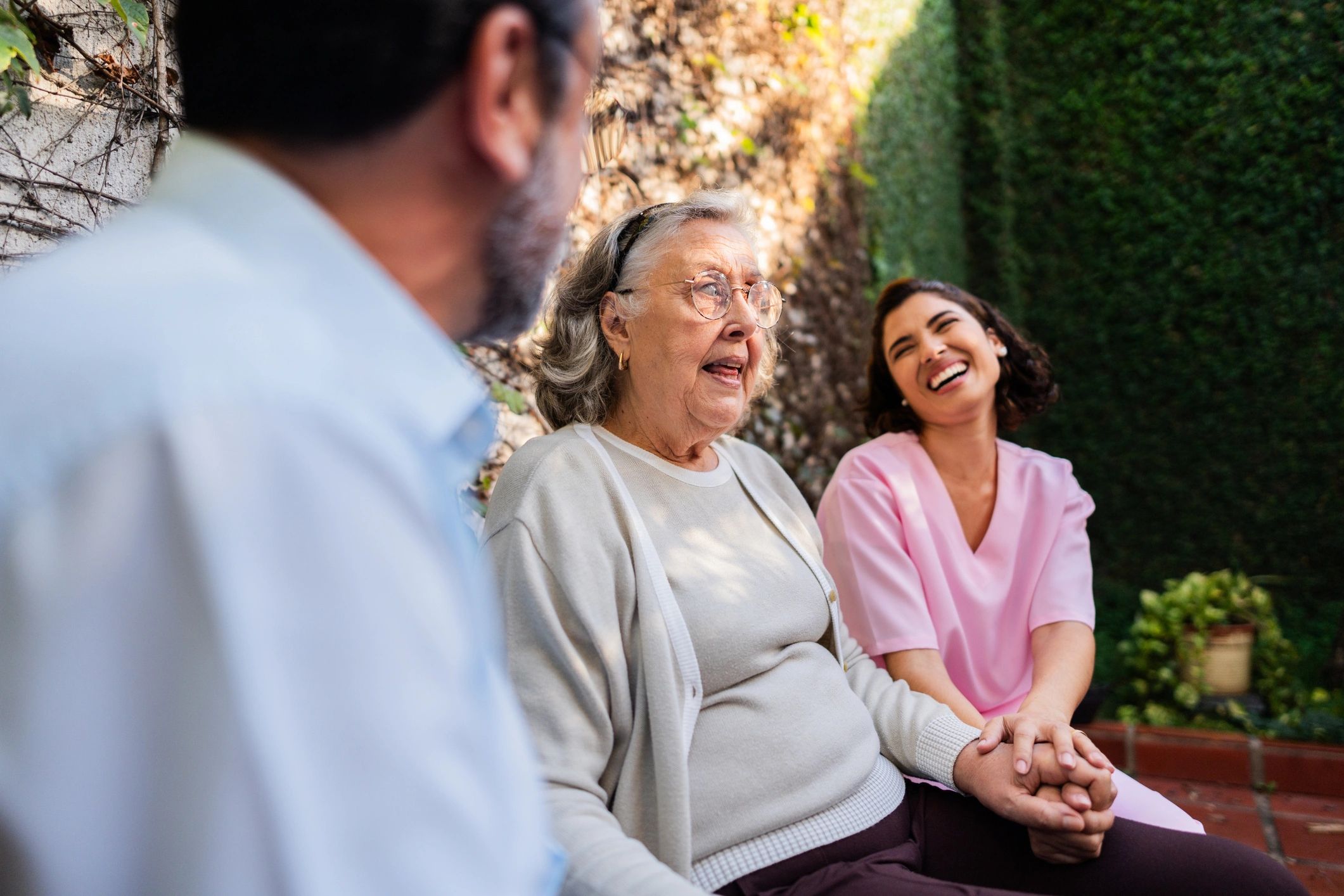 Senior woman talking with her son and a nurse during a care home visit