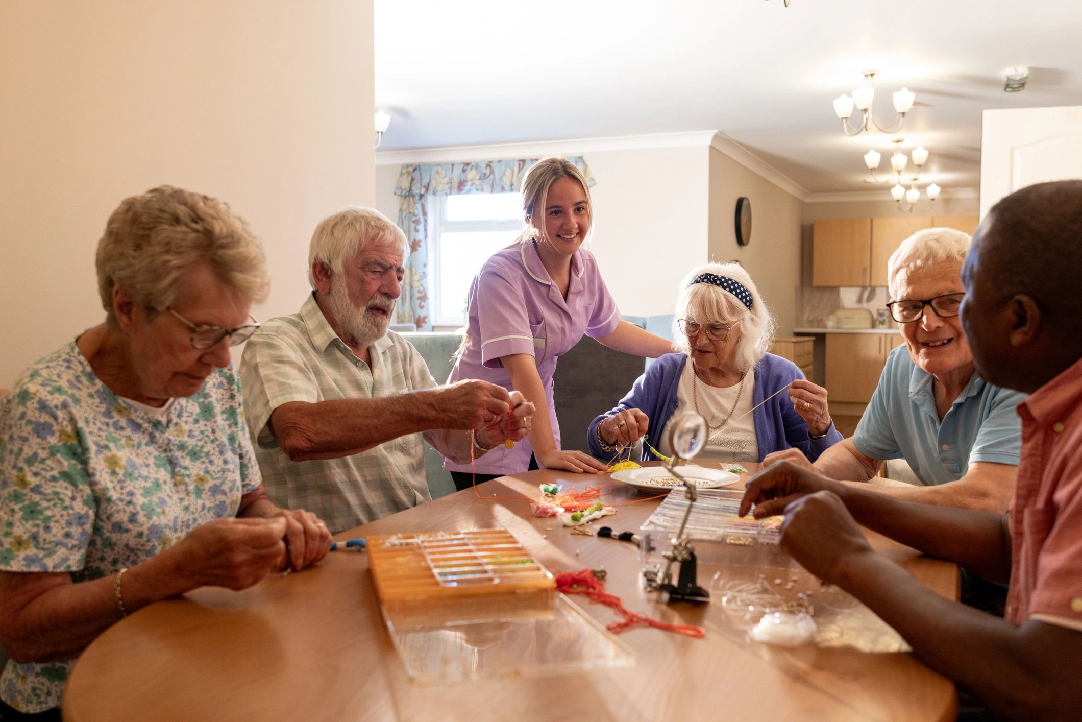 Residents taking part in a group craft activity with a caregiver nearby