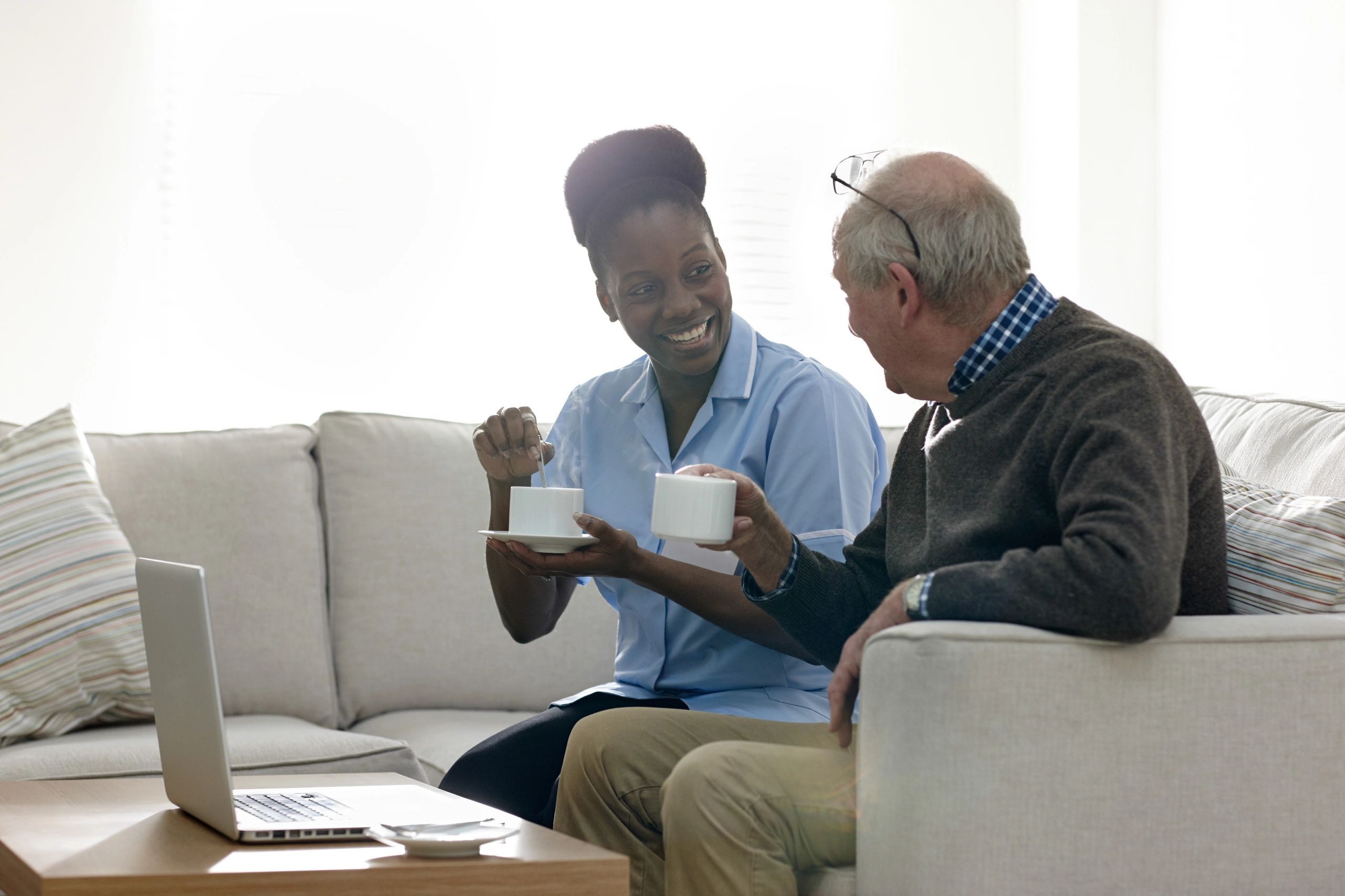 Care professional chatting with an older resident over a cup of tea
